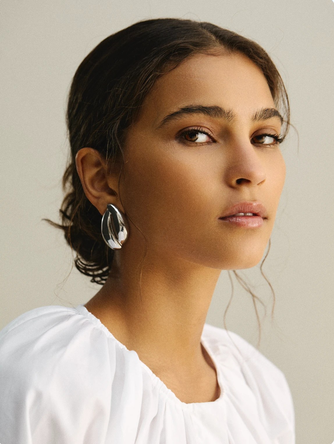 Gordon Stabbins portrait of a model in a white blouse and silver sculptural earring